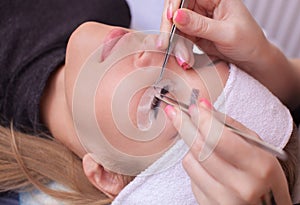 Makeup Master corrects, and strengthens eyelashes beams, holding out a pair of tweezers