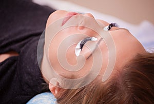 Makeup Master corrects, and strengthens eyelashes beams, holding out a pair of tweezers in a beauty salon.