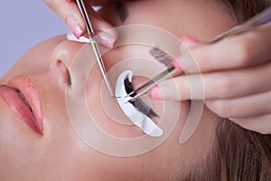 Makeup Master corrects, and strengthens eyelashes beams, holding out a pair of tweezers photo