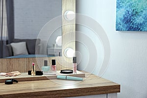 Makeup mirror on table near white wall