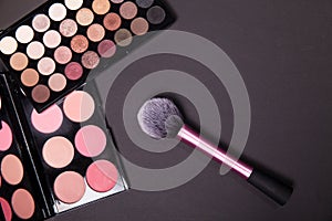 Makeup palets and brush on pure black background.