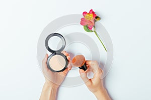 Makeup powder and brush in female hands