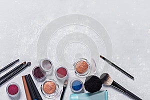 Makeup products with cosmetic, brushes, pencils, eye shadow, hand cream, with the edge from the photo below, brown background, clo