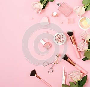 Makeup products, decorative cosmetics and pink roses on pink background  flat lay