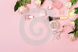 Makeup products, decorative cosmetics and pink roses on pink background  flat lay