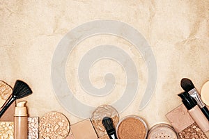 Makeup products to even skin tone and complexion on kraft paper. Makeup primer, foundation, powder with make-up brushes