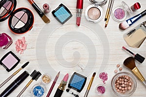 Makeup products on wooden background with copy space in center