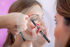 Makeup professional artist applying base color eyeshadow on model eye
