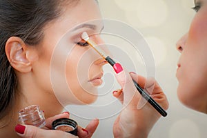 Makeup professional artist applying base color eyeshadow on model eye