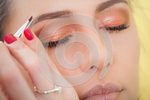 Makeup professional artist applying base color eyeshadow on model eye