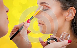 Makeup professional artist applying eyeshadow on woman model
