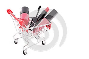 Makeup in pushcart on white background. Red lipstick, mascara, pink lip gloss, powder, nail polish. Makeup products in sh