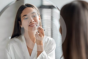 Makeup Routine. Beautiful Young Woman Applying Nude Lipstick On Lips Near Mirror