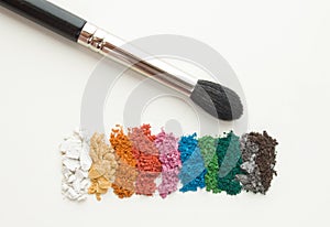 Makeup artist accessories for eyemakeup. Brush with crushed colorful eyeshadows on white background