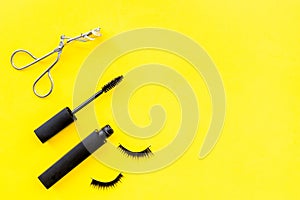 Makeup set for expressive eyelashes. Mascara, false eyelashes, eyelash curler on yellow background top view space for