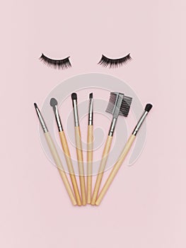 Makeup tools and false eyelashes on a pink background