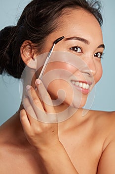 Makeup. Woman brushing brows with eyebrow brush closeup portrait