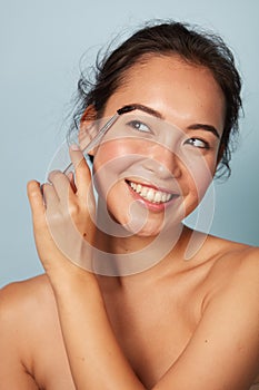 Makeup. Woman brushing brows with eyebrow brush closeup portrait