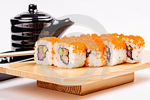 Maki Sushi made of Salmon, Red caviar, cucumber, avocado and cream cheese on black stone on wood plate. Japanese cuisine