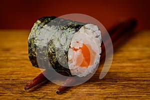 Maki sushi roll on chopsticks photo