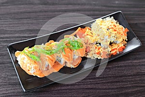Maki sushi roll made of salmon top with wakame seaweed and special sushi top with crispy tempura flour, mayonnaise and flying fish