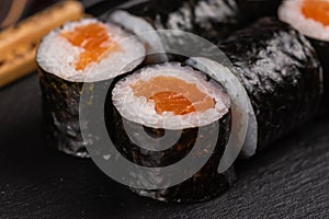 Maki sushi roll with salmon avocado and tobiko caviar served on black board close-up - Japanese food