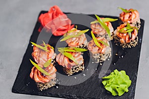 Maki Sushi Rolls with salmon on black stone on dark background. With ginger and wasabi. Sushi menu. Japanese food