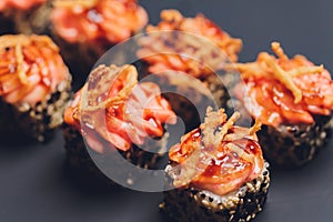 Maki Sushi Rolls with salmon on black stone on dark background. With ginger and wasabi. Sushi menu. Japanese food