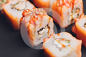 Maki Sushi Rolls with salmon on black stone on dark background. With ginger and wasabi. Sushi menu. Japanese food