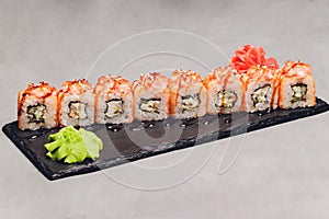 Maki Sushi Rolls with salmon on black stone on dark background. With ginger and wasabi. Sushi menu. Japanese food