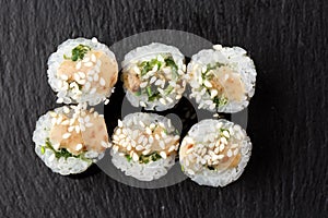 Maki Sushi Rolls with wakame and nut sauce on black stone on dark background. Sushi menu. Japanese food. Closeup of delicious