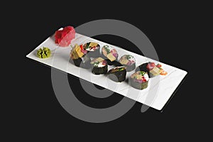 Maki Sushi set on a white plate over black background. Japanese cuisine concept, maki rolls