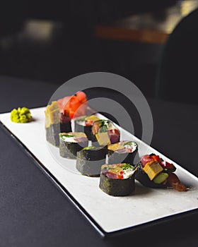 Maki Sushi set on a white plate over black background. Japanese cuisine concept, maki rolls