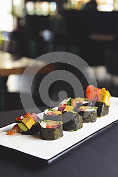 Maki Sushi set on a white plate over black background. Japanese cuisine concept, maki rolls