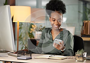 Making that all important call. an attractive young businessman sending a text while working at her desk in the office.