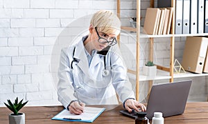 Making appointment to family doctor. Female doctor in glasses, speaks on smartphone