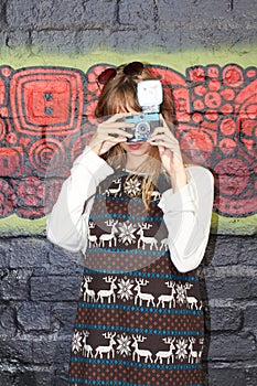 Making art with style. Portrait of a stylish young girl taking a picture with a vintage camera in front of a graffiti