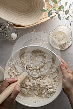 Making bread wheat with sourdough starter. Homemade breadmaking, female hand over white bowl cooking bread.