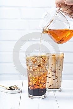 Making bubble tea, pouring blend milk tea into brown sugar pattern drinking glass cup