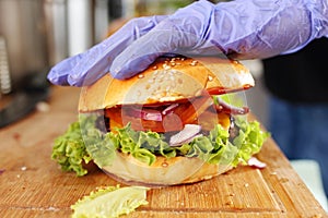 Making burgers. Preparing a hamburger in a protective gloves, in a food truck, in a fast food restaurant, close up.