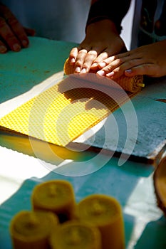 Making candle from honey bee wax plate at market.