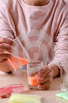 Making candles by yourself . Little girl making candle in the glass from soy wax parsley flakes