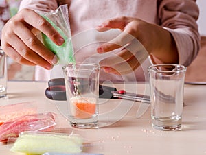 Making candles by yourself . Little girl making candle in the glass from soy wax parsley flakes