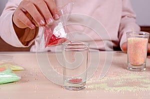 Making candles by yourself . Little girl making candle in the glass from soy wax parsley flakes.