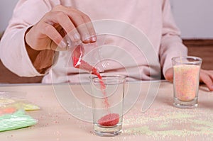 Making candles by yourself . Little girl making candle in the glass from soy wax parsley flakes.