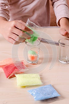 Making candles by yourself . Little girl making candle in the glass from soy wax parsley flakes