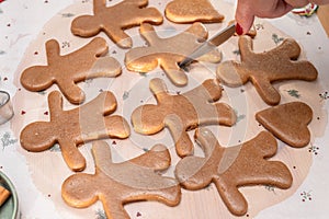 Making Christmas cookies - gingerbread men, woman is cutting out the cookies with molds photo