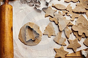 Making christmas gingerbread cookies, flat lay. Raw dough in shape of christmas tree and metal cutters, wooden rolling pin, anise