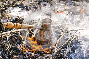 Making coffee in cezve on the bonfire when camping or hiking in the nature. Coffee on campfire