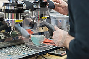 Making coffee in coffee machine. Man`s hands prepares coffee, fresh espresso pours into porcelain cup. Service and